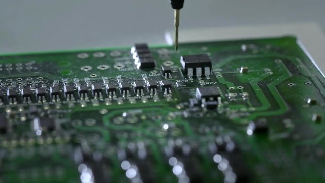 Mechanical creation process of electronic circuits. Creating an electronic board. Metal needle sets the chips on a plastic backing. Solders electronic components