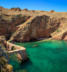 Fototapeta premium Part of the coast of Berlengas Island with the access path to Fort São João Baptista das Berlengas through stone bridges over a turquoise sea of crystalline waters, seen from the fort. In Portugal.