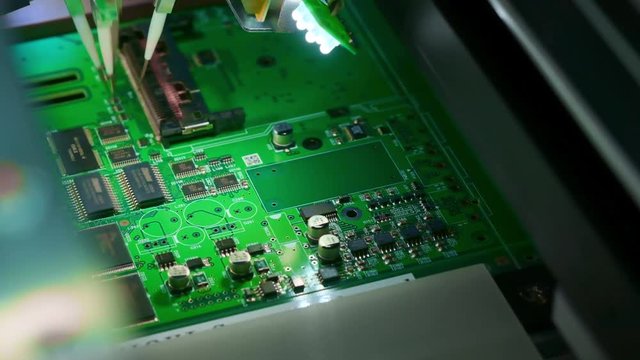 Factory Machine at Work: Printed Circuit Board Being Assembled with Automated Robotic Arm, Surface Mounted Technology Connecting Microchips to the Motherboard. Macro Close-up Footage