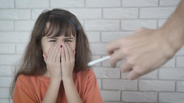 Child on the background of cigarette smoke. The child of the parent who smokes is suffering.