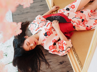 Portrait of attractive Chinese woman wearing traditional Japanese Kimono, lying on the tatami mats...