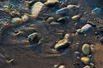 pebble stones on the sea beach, the rolling waves of the sea with foam