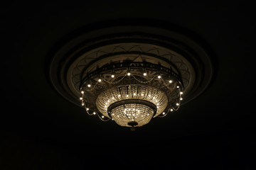 Close-up of a beautiful large crystal chandelier of round shape hanging from the ceiling in the...