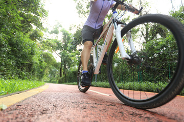 Woman cyclist riding a bike on sunny park trail in summer