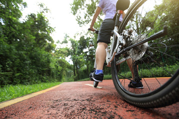 Naklejka premium Woman cyclist riding a bike on sunny park trail in summer
