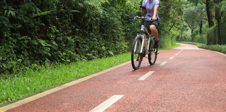 Cyclist using smart phone while riding bike on the summer forest trail