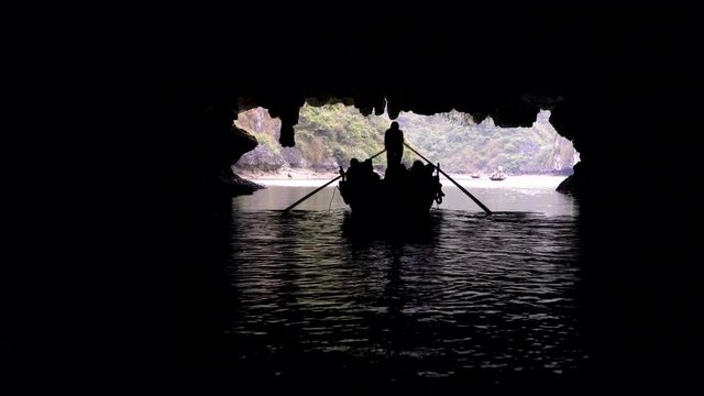 Tourists in traditional local boats being guided through the caves of the limestone islands of Ha Long Bay, Cat Ba National Park, Vietnam