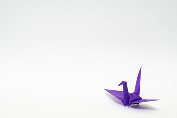 purple origami paper crane on white background