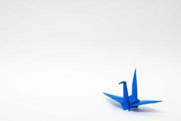 blue origami paper crane on white background