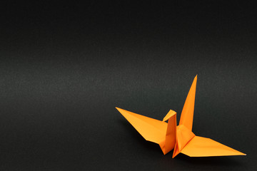 orange origami paper crane on black background