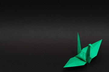 green origami paper crane on black background