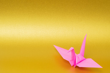 pink origami paper crane on golden background