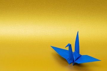 blue origami paper crane on golden background