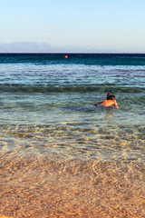 A child enjoying snorkeling in the clear sea.