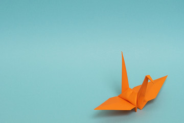 orange origami paper crane on sky blue background