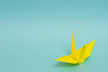 yellow origami paper crane on sky blue background