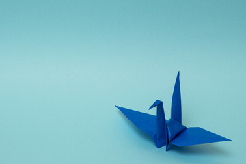 blue origami paper crane on sky blue background