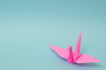 pink origami paper crane on sky blue background