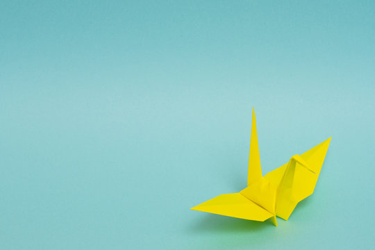 yellow origami paper crane on sky blue background