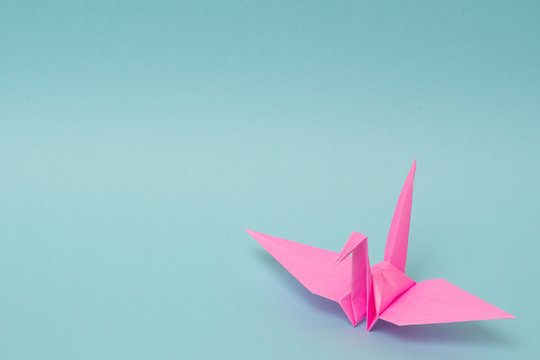 pink origami paper crane on sky blue background