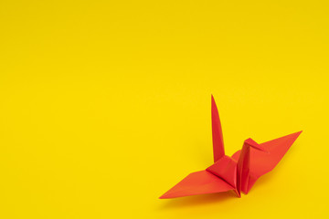 red origami paper crane on yellow background