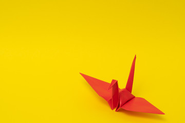 red origami paper crane on yellow background