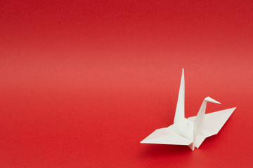 white origami paper crane on red background © Akira Ito