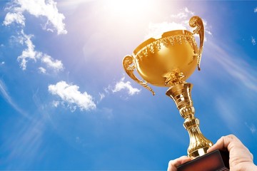 Hands holding golden trophy on a light background