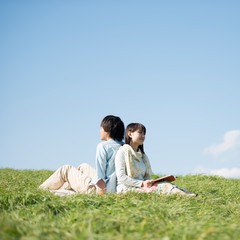 草原で音楽を聴く男性と読書をする女性