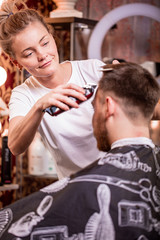 The master cuts the hair and beard of a man in a barbershop, a hairdresser does a haircut for a young man. Beauty concept, self care.