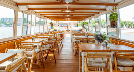 The interior of the urban river ship, with a panoramic view of the urban landscape. The concept of tourism, recreation, walking around the city, rest in the city. River transport.