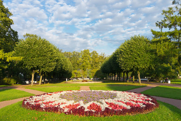 Saint Petersburg. Beautiful Smolny city park with flower beds, shady alleys, fountains and green lawns  in sunset light. Natural background. Cityscape. Comfortable urban environment