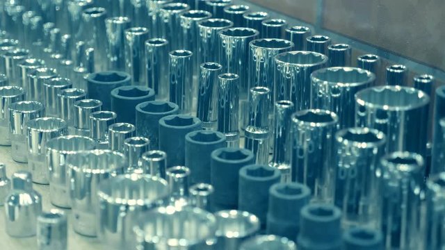 A huge number of heads to the wrenches are in rows on the shelves of the store and shine in the light. Shot in motion