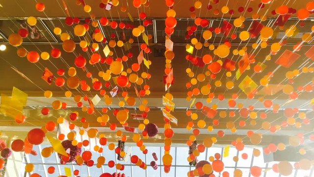 Hanging decotation from plastic balls and plates moving shining on sun