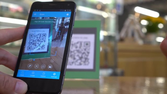 QR code cashless payment. Scan to pay system. Business or technology concept : young man using smartphone for scanning QR code for paying in the cafeteria