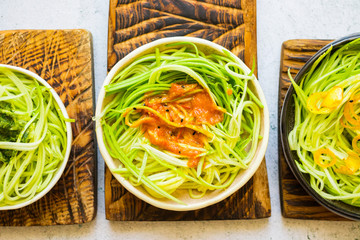 Green zucchini spaghetti or pasta with sauce. Vegan, vegetarian healthy food. White background table.