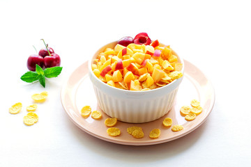 Healthy breakfast with cornflakes and pieces of fruit, cherries on a white background