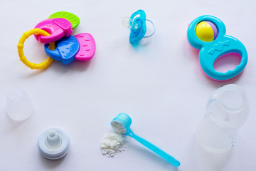 Baby milk powder, baby bottle and children's toys on a light background flat lay