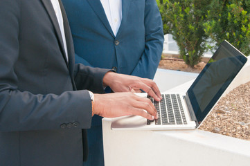 Businessman showing presentation on computer to his colleague. Hands of man in office suit using laptop. Using laptop concept