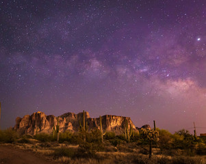 The iconic Superstition Mountains east of Phoenix, Arizona glow under the desert night sky and the...