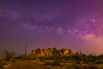 The iconic Superstition Mountains east of Phoenix, Arizona glow under the desert night sky and the epic Milky Way Our world under our universe in star filled dark skies is natural beauty