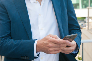Smartphone in businessman hands. Caucasian man in formal jacket using smartphone, checking email, using app or texting message. Wireless connection concept
