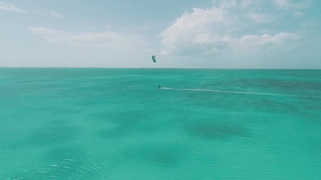 Kitesurfer speeding with kite  in clear crystal water, from drone in Los Roques venezuela Caribbean sea Moving rigth to left.