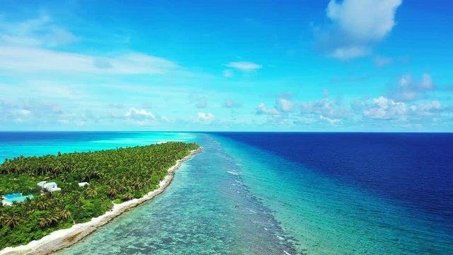 Aerial view of a tropical forest on an island and some houses. Tn the turquoise sea in Thailand. Truck left Reefs in the water and blue water on the left