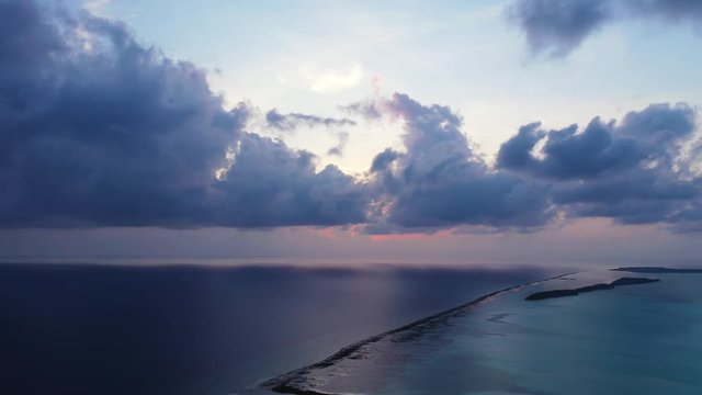 Flight above the turquoise sea in Hawaii afte sun has set. showing some distant islands and a reef. static