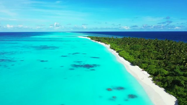 Drone view. Flight next to an exotic island with a forest on it. Turquoise water of the sea on the left, in Indonesia. Pedestal up
