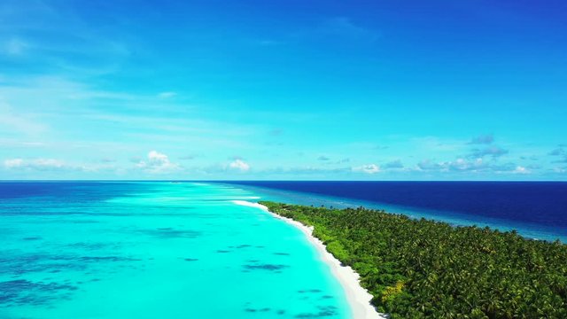 Drone view. Flight next to an exotic island with a forest on it. Turquoise water of the sea in Indonesia. Dolly out. A blue sky above