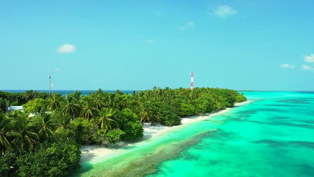 Aerial view of a tropical island in turquoise greenish water in the Philippines. Palm trees and a radio mast on the isle. Dolly out