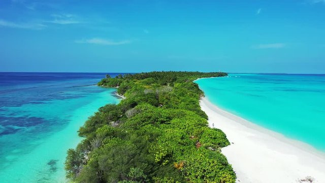 Slow fly over a tropical island in the center of the frame. Trees and beaches on the isle. The sea is turquoise and blue to both sides. Indonesia. Dolly in, Pedestal up