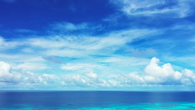 A blue sky with clouds above the  blue Philippine Sea.  one third of water. Pan right